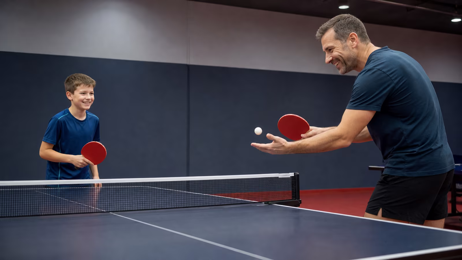 Otec hrá so synom stolný tenis a obaja sa smejú, deti vedieme k zdravej radosti