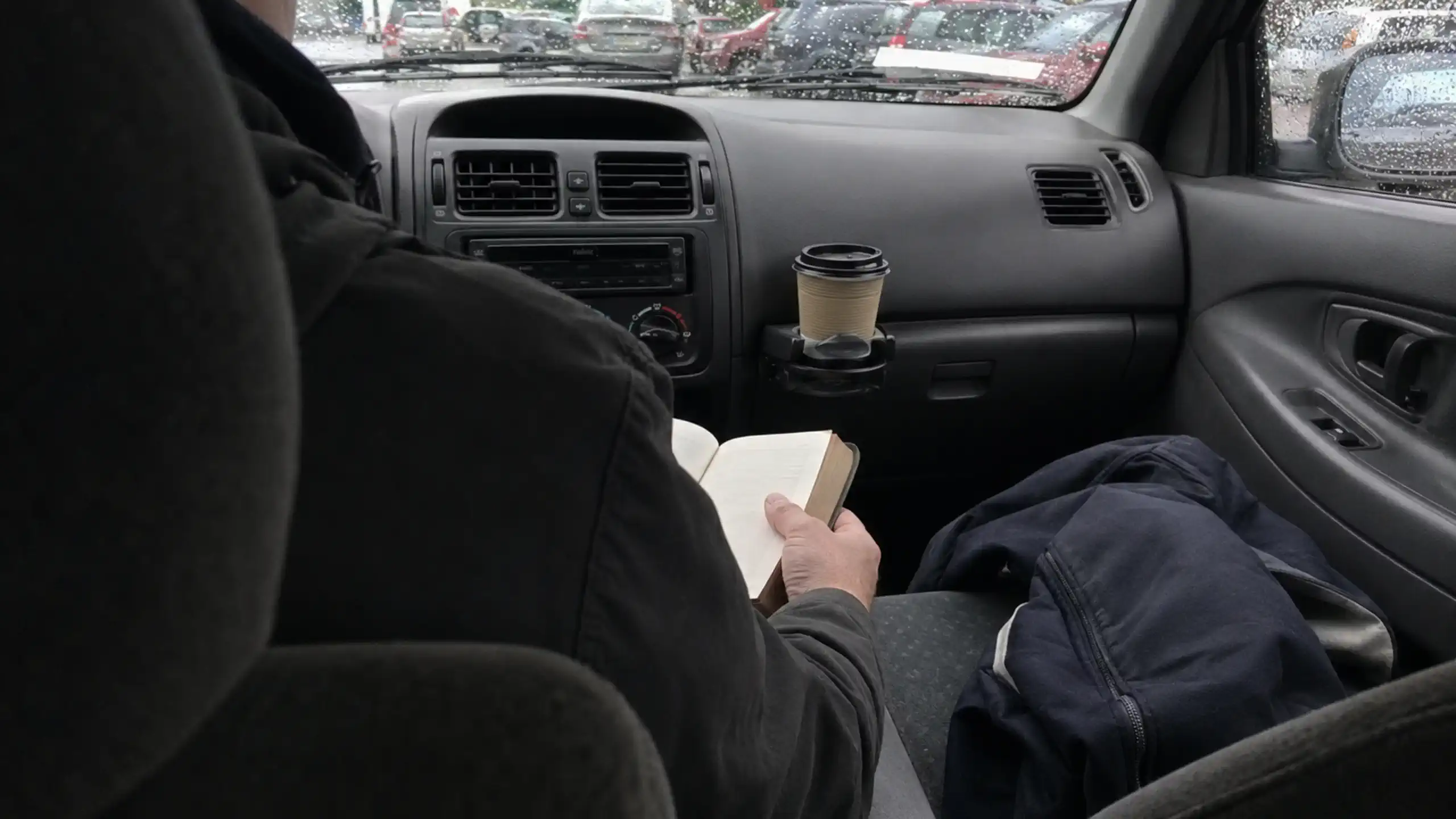 Pohľad na muža počas bežného dňa ako číta Bibliu v zaparkovanom aute
