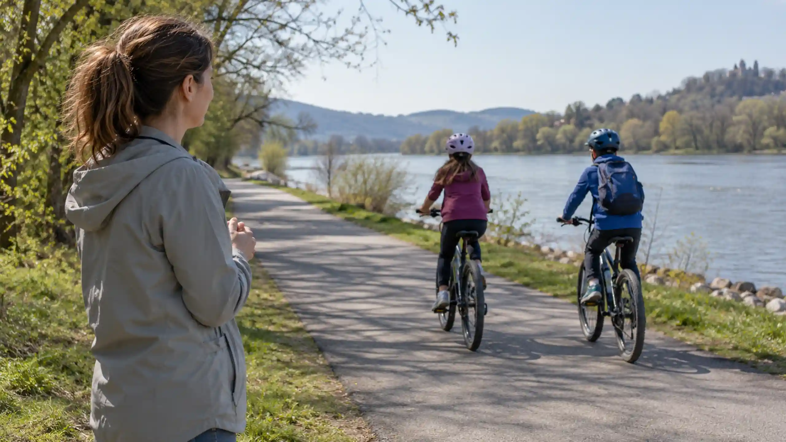 Matka s pokojom pozerá za deťmi na bicykloch.